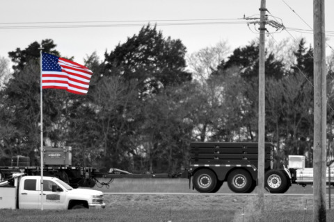 Parish Transport truck on the road, carrying an American flag flagpole